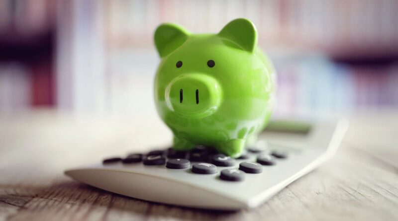 A green piggy bank on top of a calculator