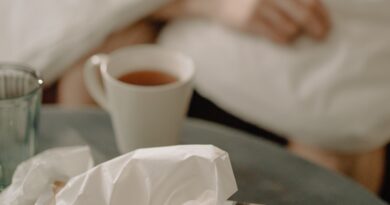 used tissues, hot tea, person wrapped in blanket